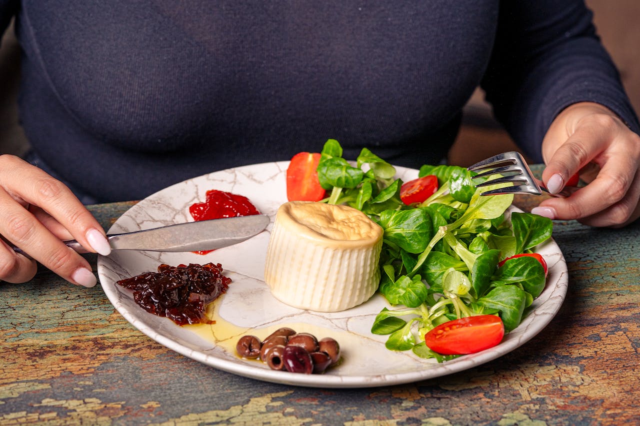 Delicious gourmet salad with fresh greens, cheese, olives, and tomatoes on a rustic plate.